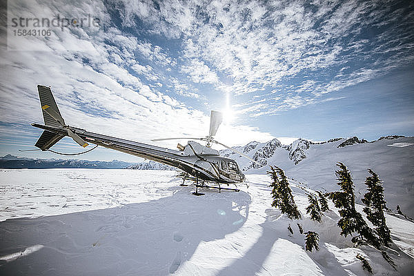 Die Sonne scheint auf einen Hubschrauber  der auf einem schneebedeckten Berg vor Christus gelandet ist.
