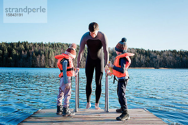 Vater und seine Kinder Kaltwasserschwimmen am Strand in Schweden