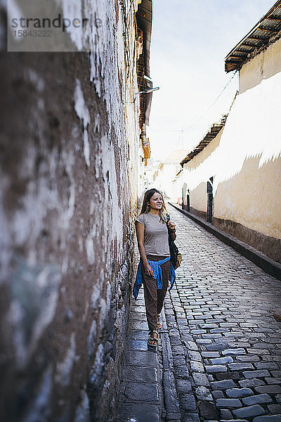 Eine junge Frau steht an einer alten Mauer in Cusco  Peru