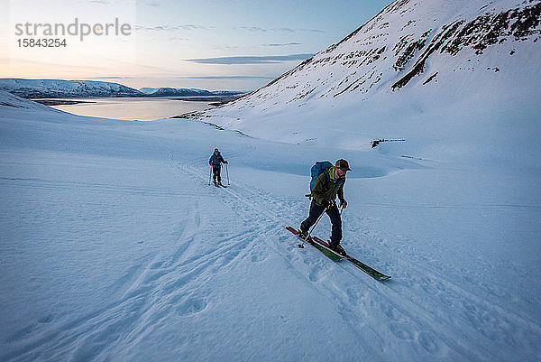 Mann und Frau beim Skilanglauf in Island mit Wasser im Rücken