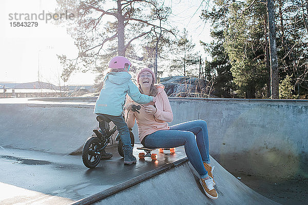 Mutter und ihre Tochter lachen beim Spielen in einem Skatepark