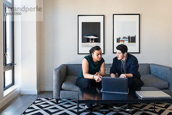 Geschäftsleute diskutieren über Laptop  während sie im Büro auf dem Sofa sitzen