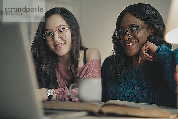 zwei junge Frauen lächeln mit einem Laptop