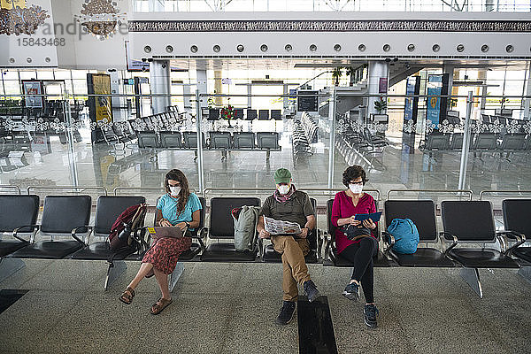 Dreiköpfige Familie  die aufgrund der globalen Gesundheitskrise durch das Coronavirus Gesichtsmasken trug  während sie auf einem verlassenen Flughafen in Khajuraho  Madhya Pradesh  Indien  wartete.