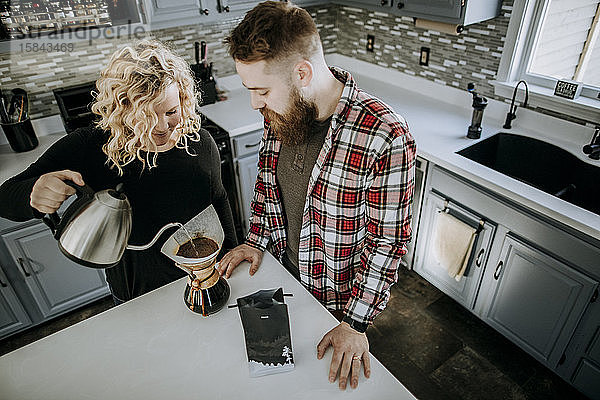 Männer- und Frauenpaar stehen zusammen in der Küche und kochen Kaffee