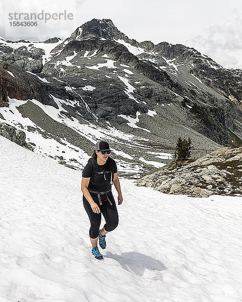 Eine Frau wandert an einem Sommertag in den Bergen für Britisch-Kolumbien auf ein Schneefeld.