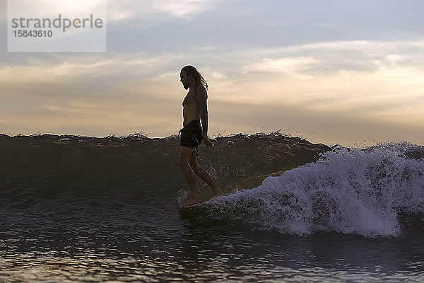 Silhouette eines Surfers bei Sonnenuntergang