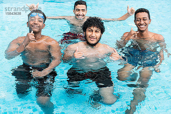 Eine Gruppe junger Menschen in einem Schwimmbecken lächelt und gestikuliert