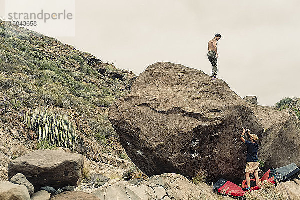 Ein männlicher Kletterer steht auf einem Felsblock
