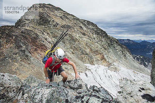 Hochwinkelaufnahme eines Rucksacktouristen  der einen felsigen Berg besteigt.