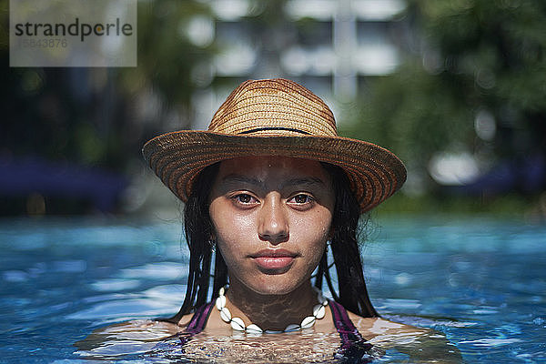 Stylisches  trendiges  junges Teenager-Viscomädchen im Pool mit Strohhut