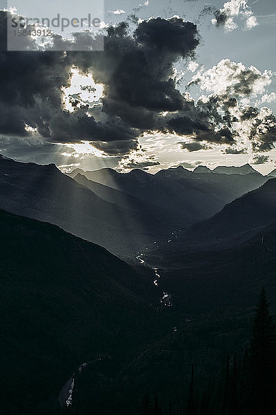 Sonne bricht durch Wolken im Bergtal  Glacier National Park