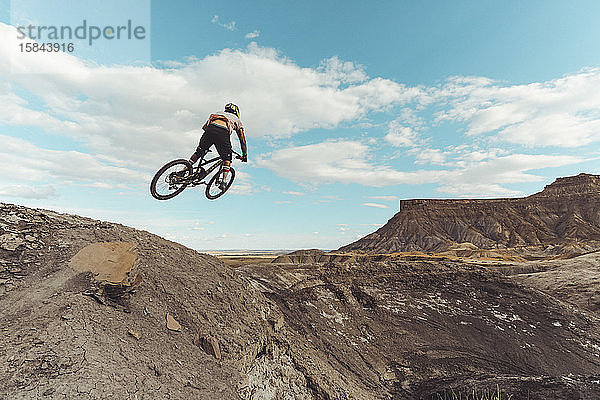 Mann springt mit Mountainbike vor dramatischen Bergen