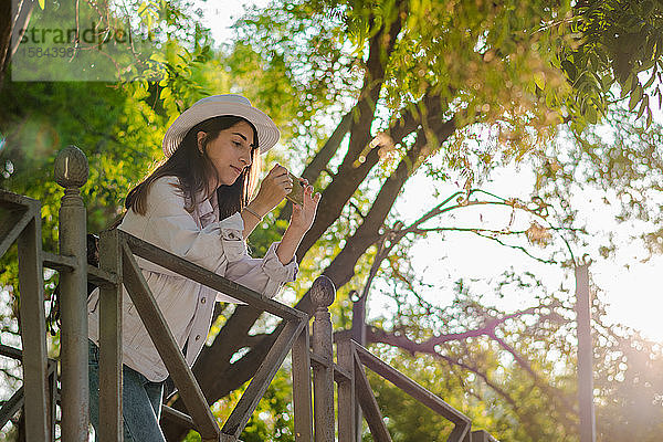 Junge Frau macht mit ihrem Smartphone ein Foto in einem Park. Freizeit  Lebensstil  Technologie
