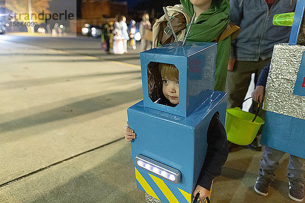Kind in selbstgemachtem Roboterkostüm steht Schlange für Süßes oder Saures