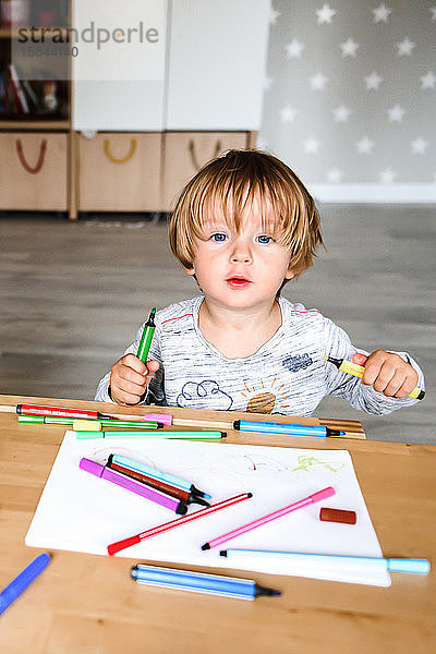 Kleiner Junge zeichnet mit Filzstiften