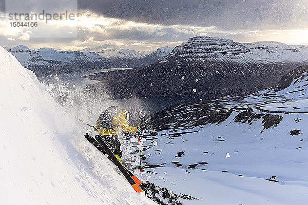 Männlicher Extremskifahrer in den isländischen Ostfjorden bei Sonnenuntergang