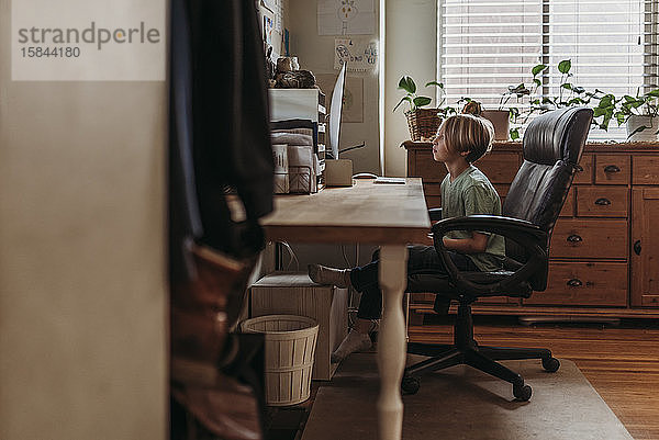 Junge im Grundschulalter  der während der Isolation Online-Unterricht vom Lehrer nimmt