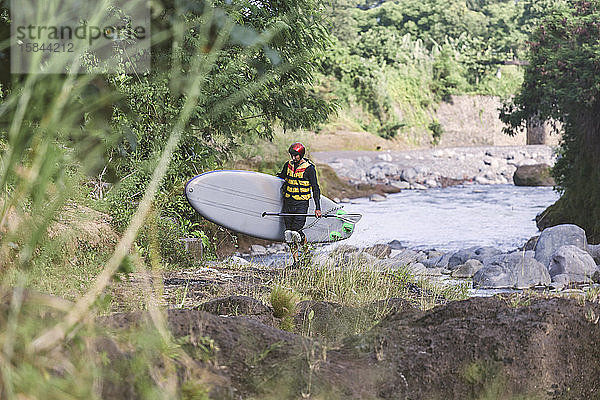 Mann mit aufrechtem Pfützen-Surfbrett