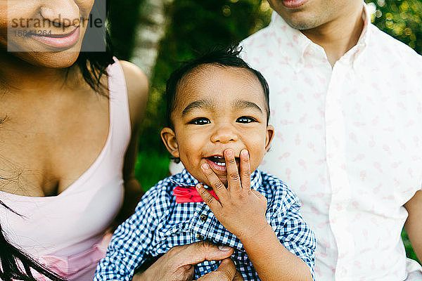 Ausgeschnittenes Porträt eines lachenden Babys  das seinen Mund bedeckt