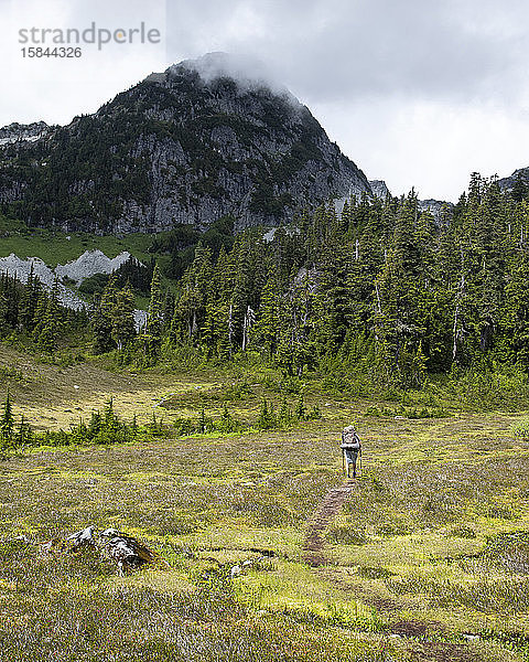 Ein Mann wandert einen Pfad entlang  um ein Wochenende in den Bergen zu zelten.
