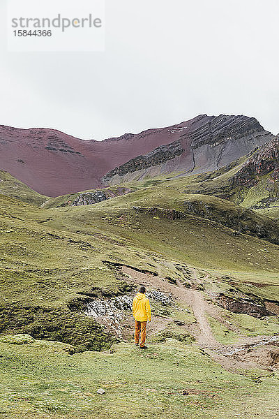 Ein Mann in einer gelben Jacke steht auf einem Hügel in Peru