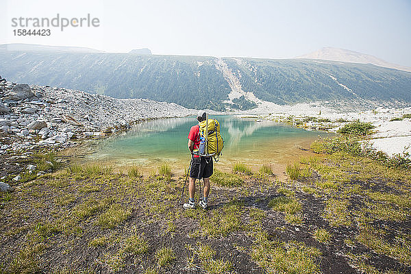 Backpacker blickt über einen wunderschönen Alpensee.