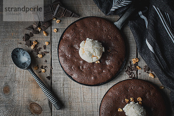 Draufsicht auf Brownies mit Eis und Nüssen in gusseisernen Pfannen.