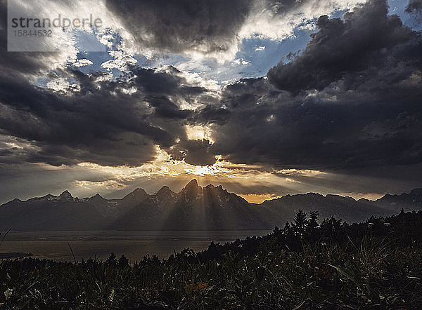 Untergehende Sonne brennt durch Wolken über den Teton-Bergen  Wyoming