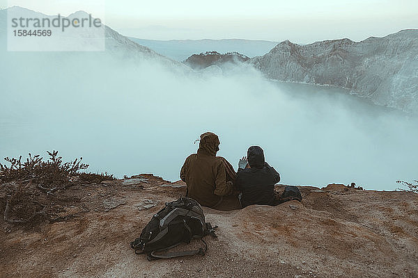 Zwei Wanderer sitzen und schauen auf den Ijen-See