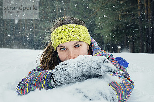 das Mädchen liegt im Schnee und lächelt