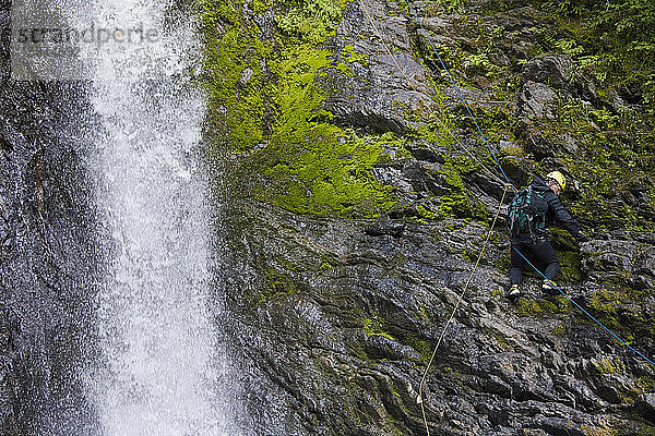Mann  der sich neben einem Wasserfall im Frost Creek Canyon abseilt.