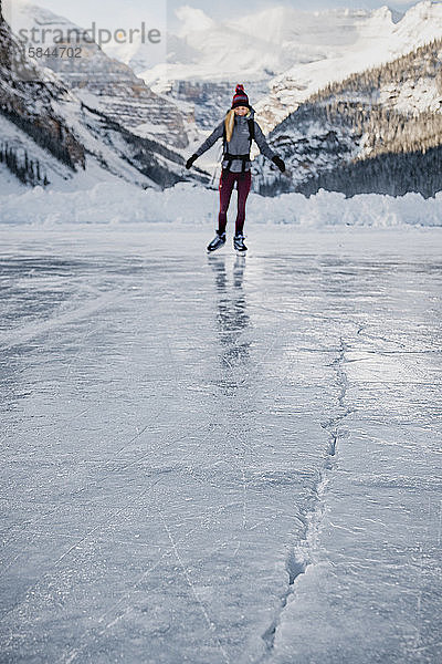 Junge Frau skatet auf gefrorenem See in Richtung Eisriss