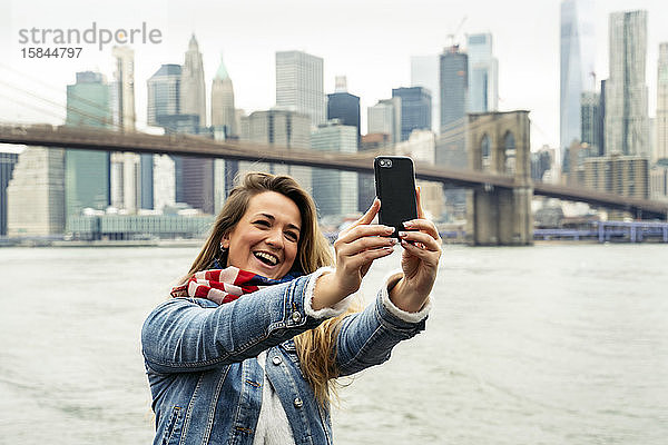 attraktive Frau  die ihr Smartphone benutzt  mit der Skyline von New York im Hintergrund