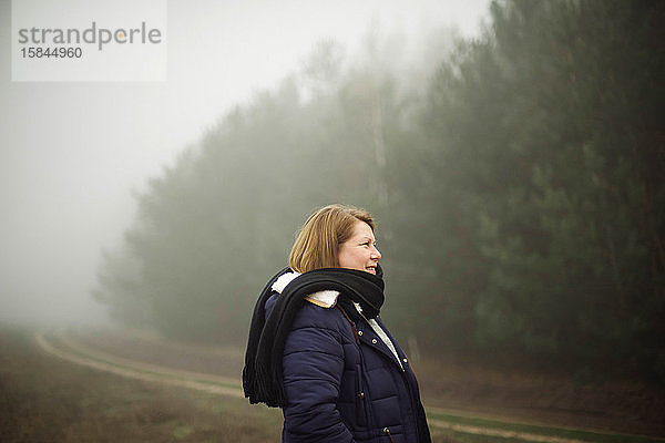 Frau steht bei nebligem Wetter am Wald