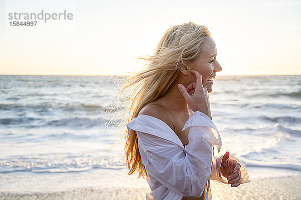 Teenager-Mädchen lacht am Strand bei Sonnenuntergang