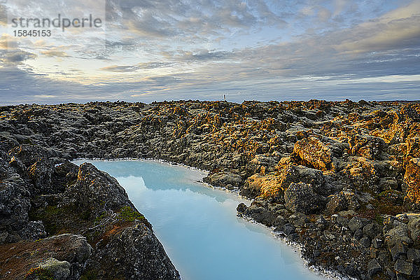 Malerische Landschaft einer geothermischen Quelle in felsigem Gelände bei Sonnenuntergang