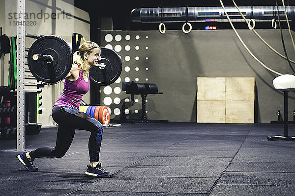 Junges Mädchen beim Gewichtheben und Lächeln in einer Crossfit-Turnhalle