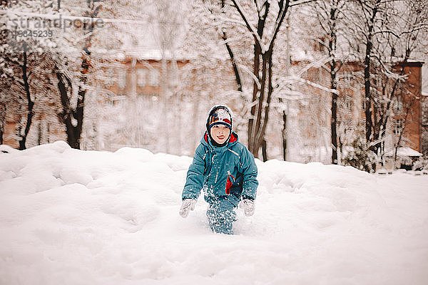 Glücklicher Junge spielt im Winter im Schnee