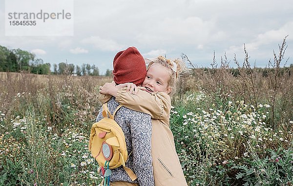 Eine Schwester  die ihren Bruder umarmte  stand im Herbst auf einem Feld mit Wildblumen