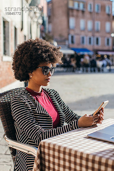 Junge Geschäftsfrau überprüft intelligentes Mobiltelefon