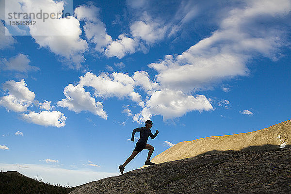 Mann rennt als Silhouette in Indian Peaks Wilderness  Colorado  auf einen Felsen