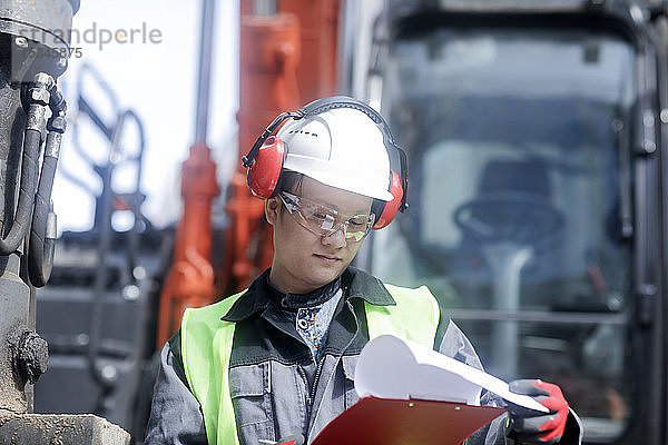 Bauingenieur  der vor einem Bagger steht