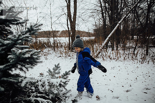 Kleiner Junge im Schneeanzug spielt im Winter im Schnee