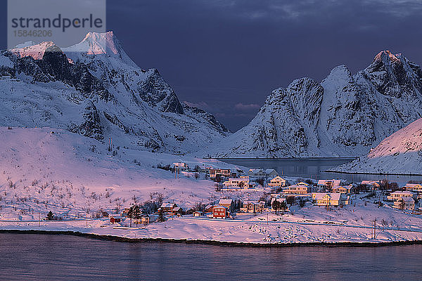 Rosa Winterlicht in der Morgendämmerung strahlt über kleines Küstendorf und Berge  Reine  MoskenesÃ¸y  Lofoten Inseln  Norwegen