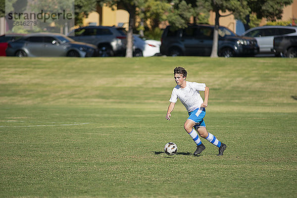 Teenager-Fussballspieler trainieren mit einem Ball in einem Park