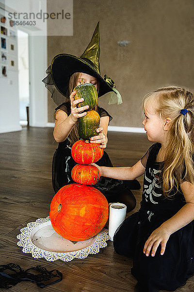 Zwei Schwestern zu Halloween in Skelettkostümen mit Kürbissen gekleidet