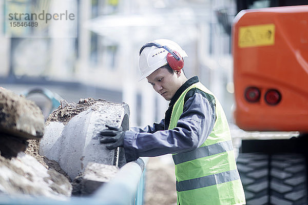 Bauingenieur  der vor einem Bagger steht