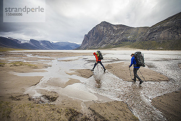Zwei Rucksacktouristen überqueren Ströme am Akshayak-Pass  Baffin Island.