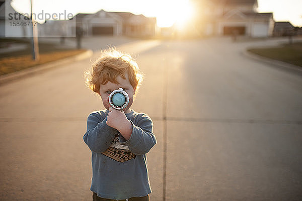 Kleinkind Junge zielt draußen in der Nachbarschaft auf Spielzeugpistole